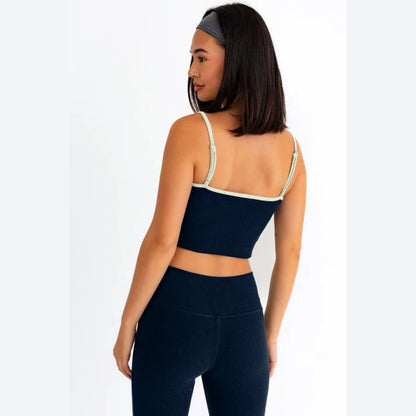 Back view of navy blue athletic crop top featuring adjustable white straps and seamless ribbed fabric construction