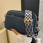 Navy crossbody bag with bold black-and-white chevron strap, a stylish and functional accessory.