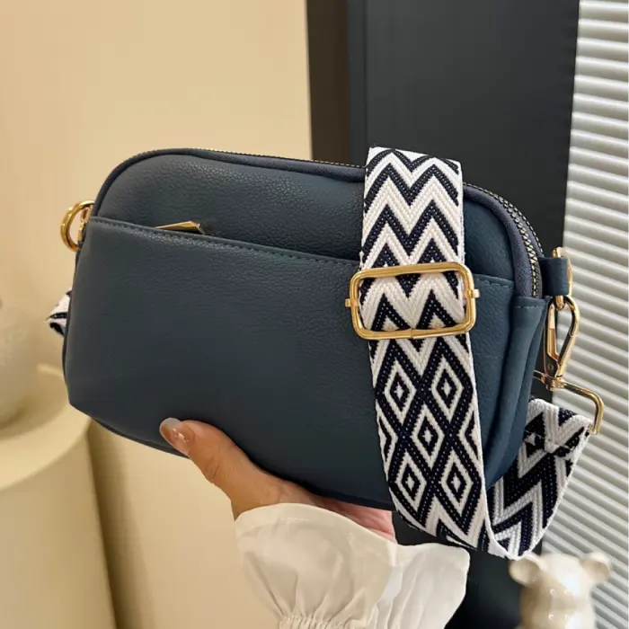 Navy crossbody bag with bold black-and-white chevron strap, a stylish and functional accessory.