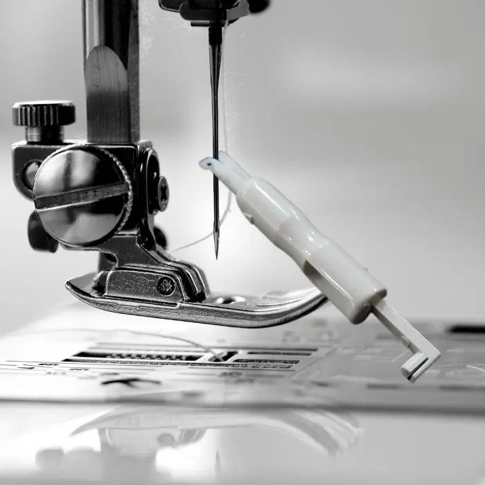 Needle threader positioned near sewing machine needle and foot in grayscale tone setting.
