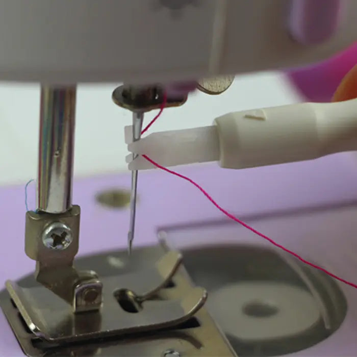 Needle threader assisting thread placement through machine needle eye with close-up view.