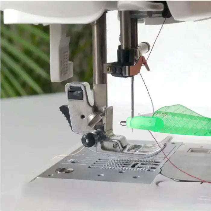 Needle threader tool in use on sewing machine showing close-up threading process with green handle tool