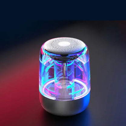 Glowing wireless speaker with blue and pink neon lights, transparent body, silver top, on a dark background