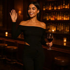Off shoulder top paired with matching pants in an elegant bar setting with warm ambient lighting and woman holding wine glass