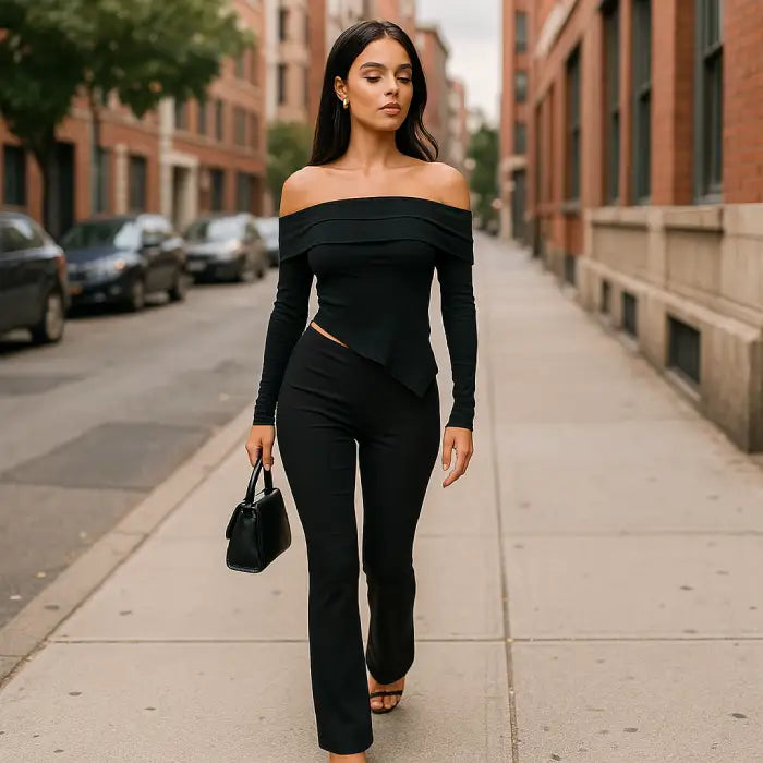 Off shoulder top with asymmetrical cutout detail paired with flared pants for sophisticated urban street style with handbag accessory