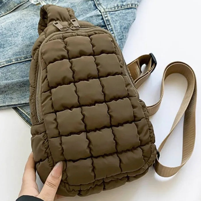 Olive green quilted sling backpack with zipper closure and adjustable strap, displayed on white background