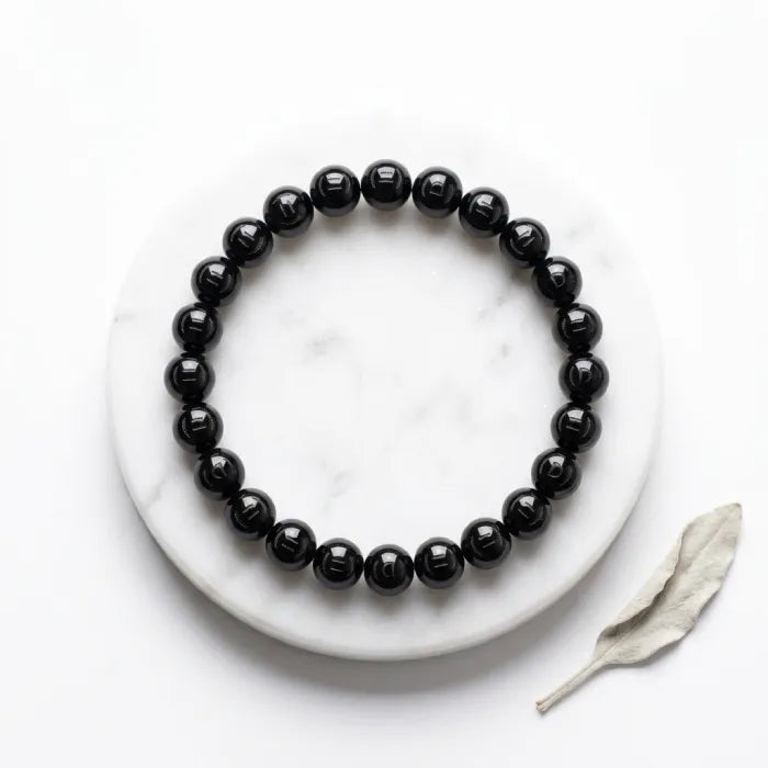 Onyx Bracelet with polished black beads on white marble surface, timeless minimalist jewelry for everyday style and grounding
