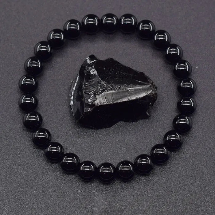 Onyx Bracelet with polished black beads and raw crystal centerpiece on dark surface, powerful protection jewelry for grounding energy