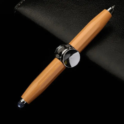 Orange fidget spinner pen featuring a chrome center on a black leather surface.