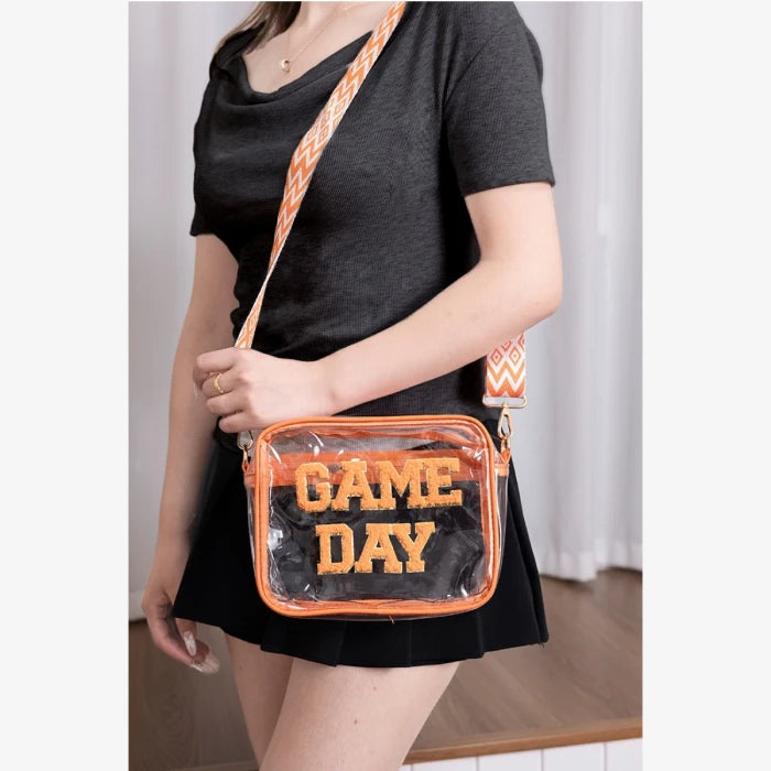 Clear stadium compliant bag in orange trim shown styled with black dress for game day fashion accessories