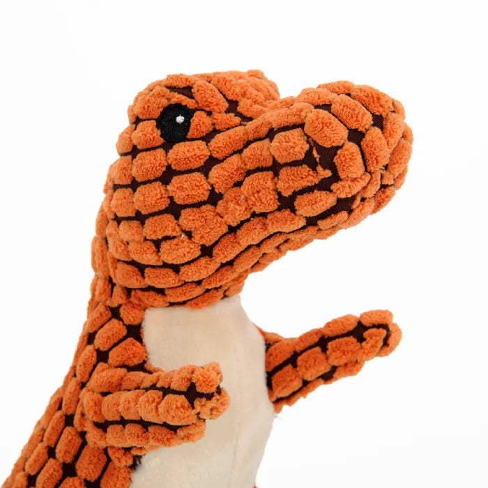 Close-up of an orange plush dinosaur dog toy with textured patterns and black eyes.