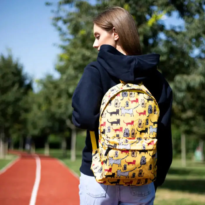 Back view of a person wearing a yellow cat-patterned backpack, perfect for casual or school use.