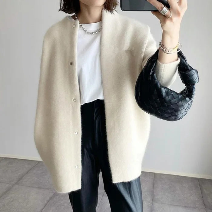 Oversized knit cardigan in creamy white wool worn casually with black pants for a soft minimalist style