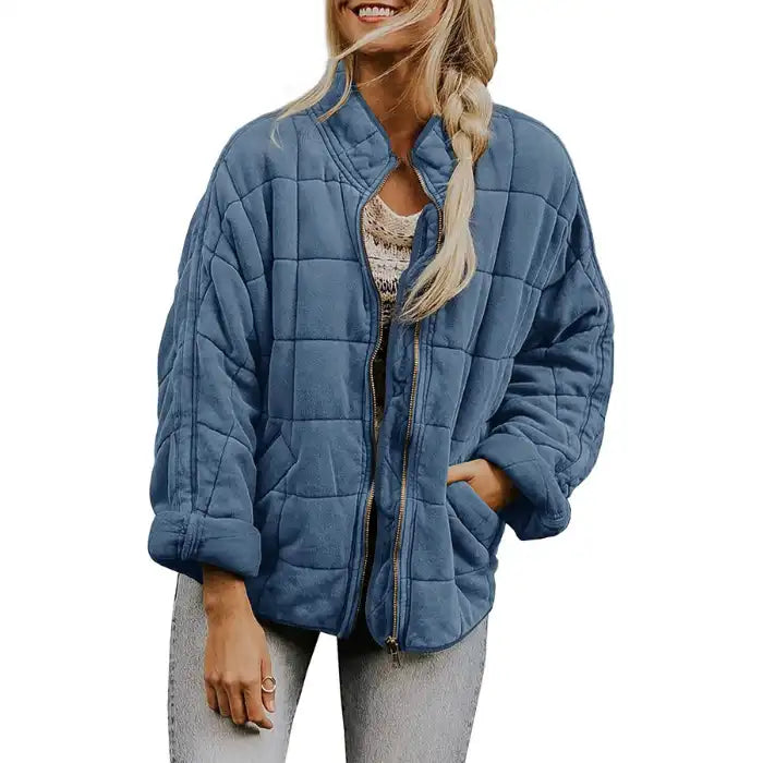  Oversized quilted zip jacket in dusty blue with square quilting and side pockets, front view.