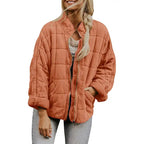 Oversized quilted zip jacket in orange with collarless neckline and square quilting, front view.