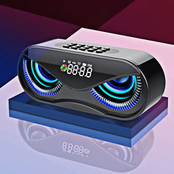 Black oval speaker with two illuminated circular displays resembling owl eyes, digital clock, and control buttons on geometric background