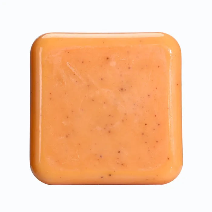 Pale orange natural exfoliant soap bar with visible granules, isolated.