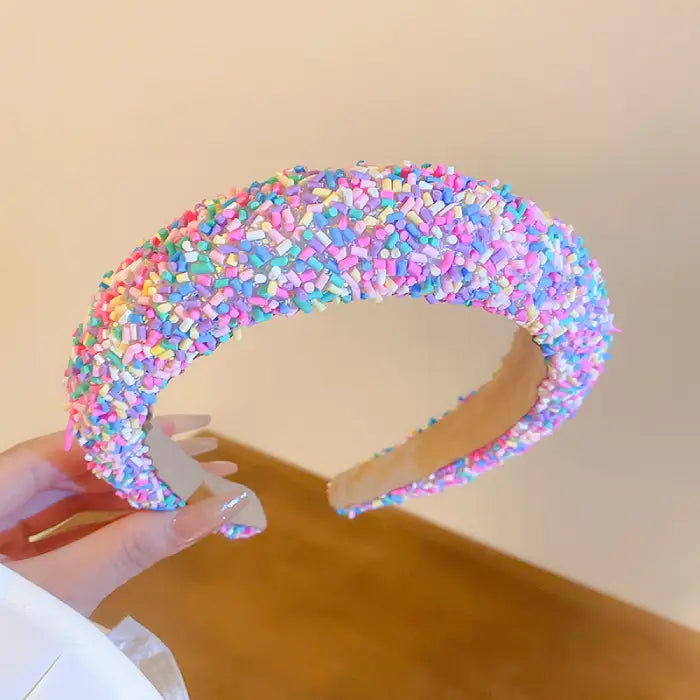 Close-up of padded headband with dense pastel pink, blue, and purple confetti-like texture