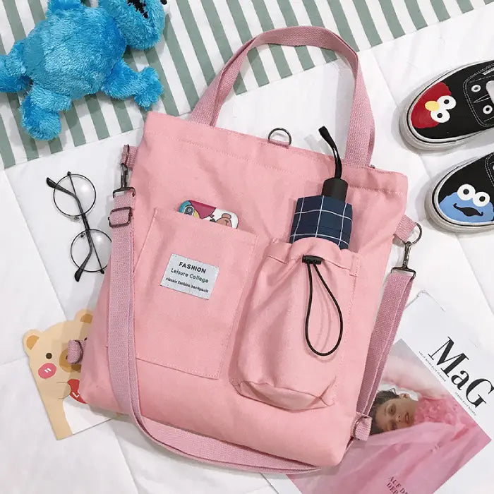 Pink canvas tote bag with umbrella holder and pockets styled with glasses and plush toy