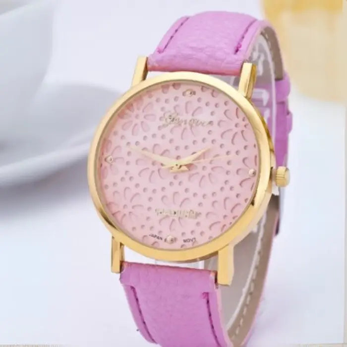 Pastel pink women's watch with a gold floral-patterned dial and pastel pink leather strap.