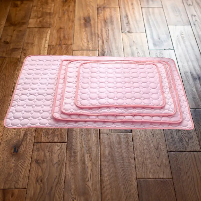 pet cooling pad collection showing stacked pink cooling mats in three different sizes with quilted bubble-pattern design