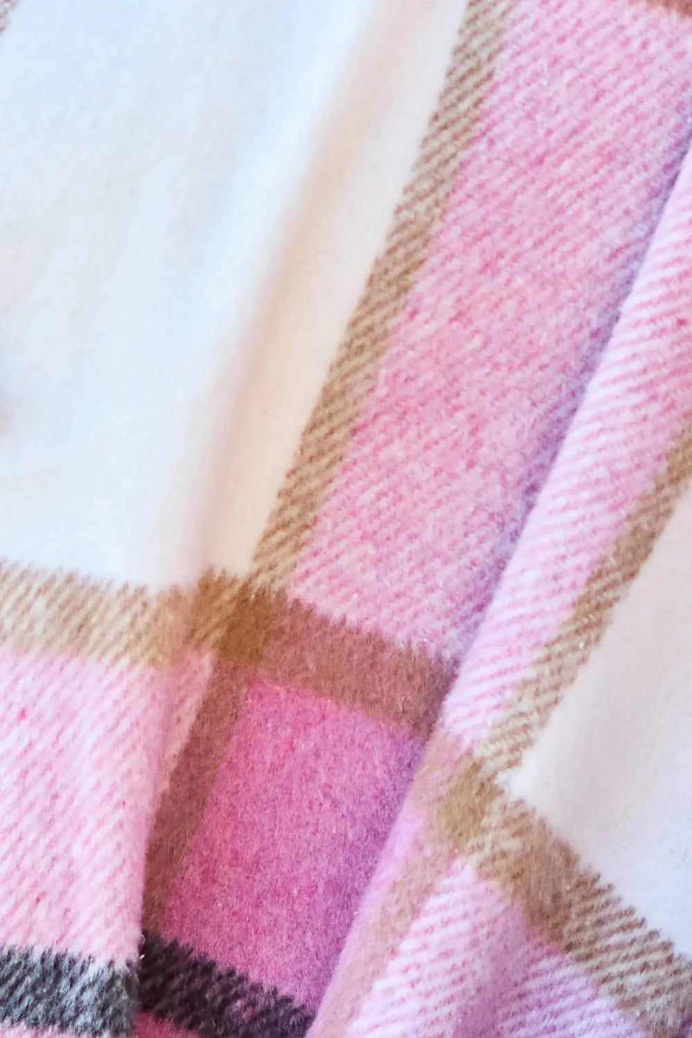 Close-up of the pink and white plaid wool coat fabric showing its soft texture and detailed pattern.