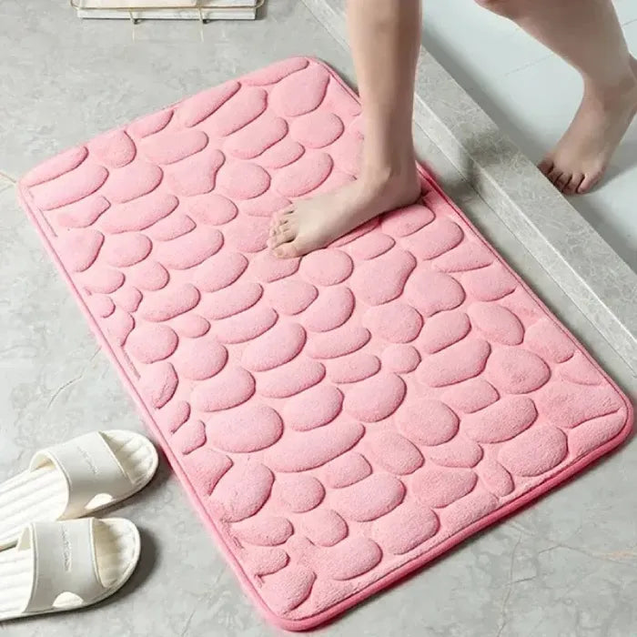 Pink scalloped bathroom mat with human feet, ideal for home comfort.