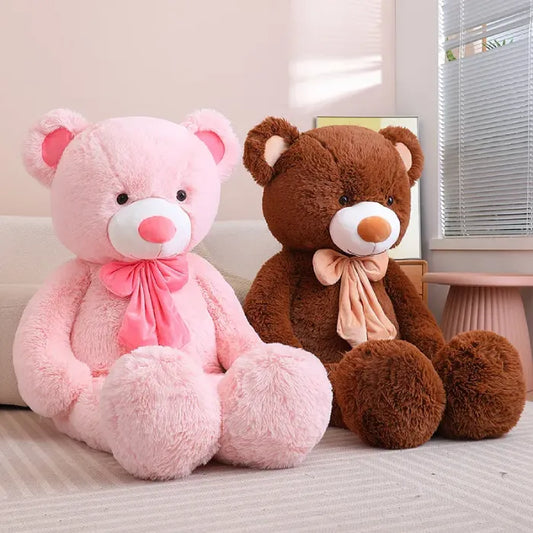 Young woman sitting with giant pink and gray teddy bears on a couch.