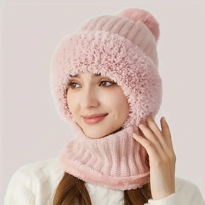 Person wearing a pink faux fur knit hat with a pom pom and matching neck warmer