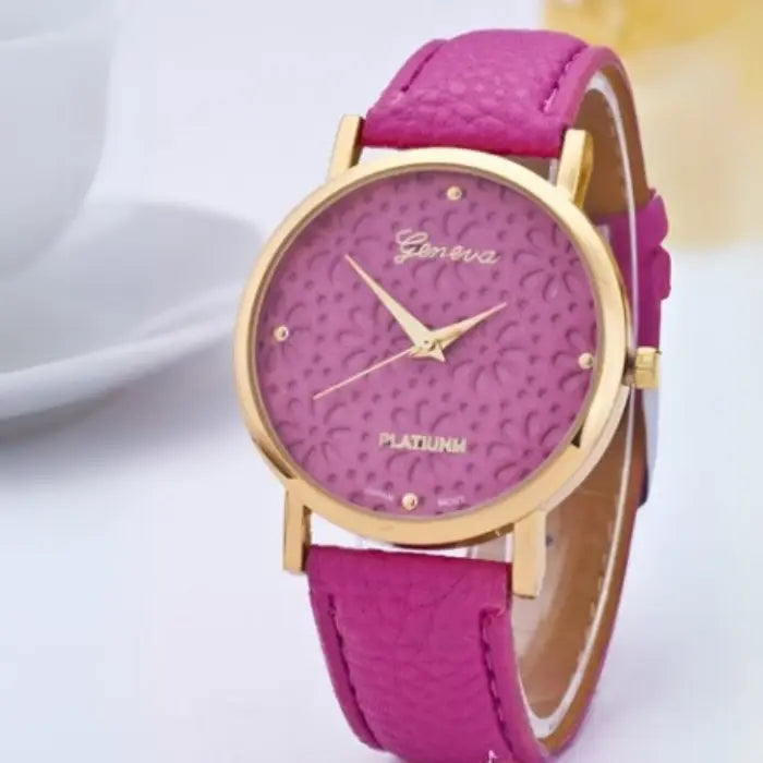 Pink women's watch with a gold floral-patterned dial and pink leather strap.