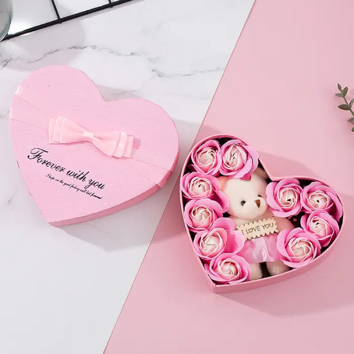 Open pink heart-shaped gift box with teddy bear and pink artificial roses, perfect for romantic gifting.