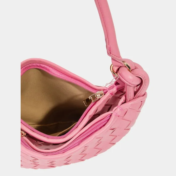 Pink handbag interior with gold lining, visible zipper, and knotted strap detail