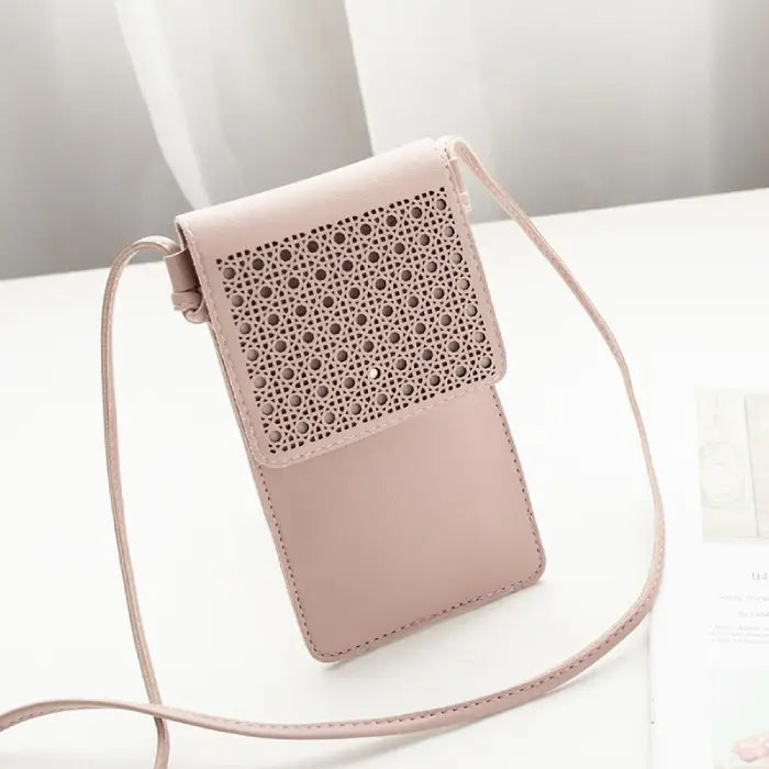 Pink leather phone pouch with perforated flap design and long strap for convenient crossbody use.