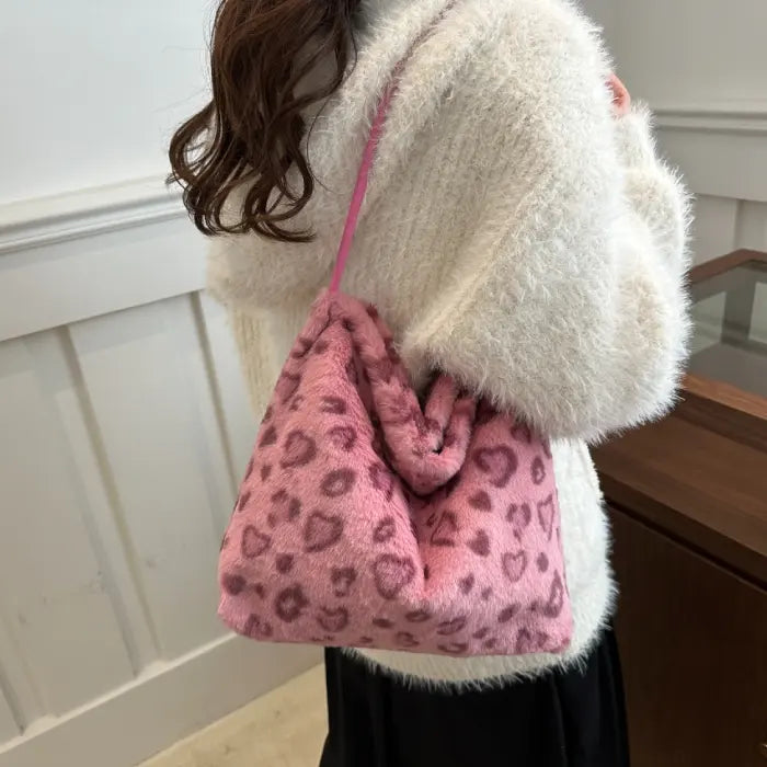 Pink leopard print faux fur handbag worn on the shoulder with a matching pink strap for a stylish look.