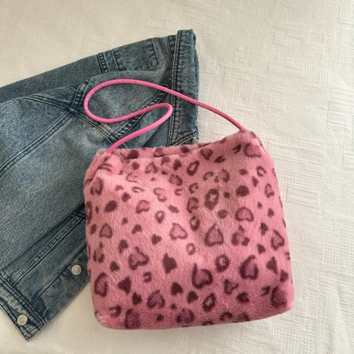 Pink leopard print faux fur handbag paired with denim jeans for a chic and fashionable look.