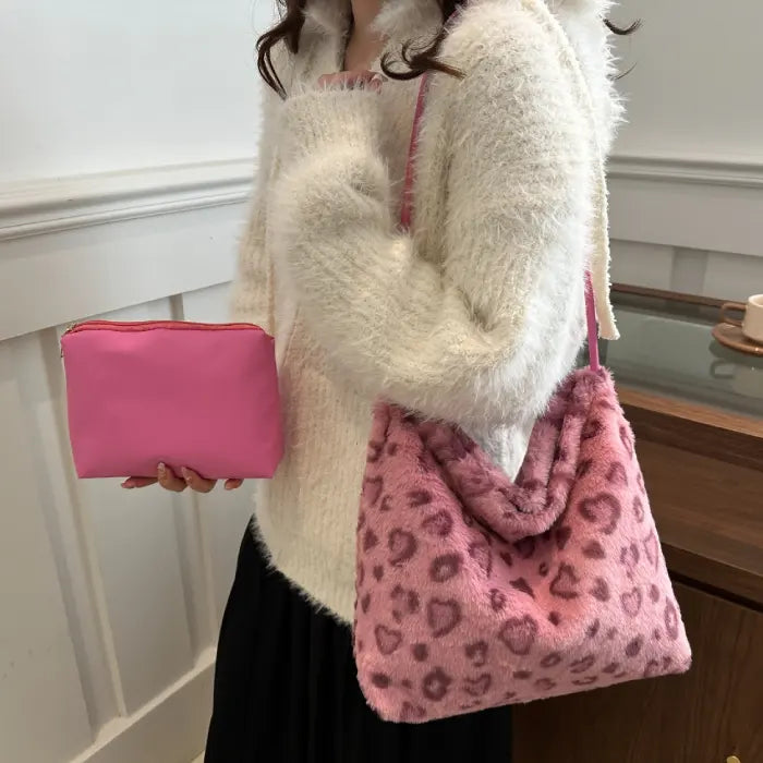 Woman holding pink leopard print faux fur handbag with matching pink pouch for a trendy look.