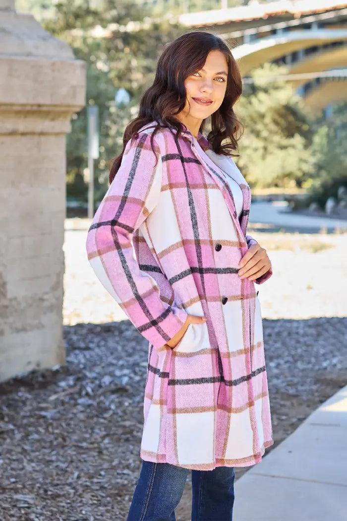 Woman in a pink plaid wool coat with a button closure, styled with jeans and a white top in an outdoor setting.