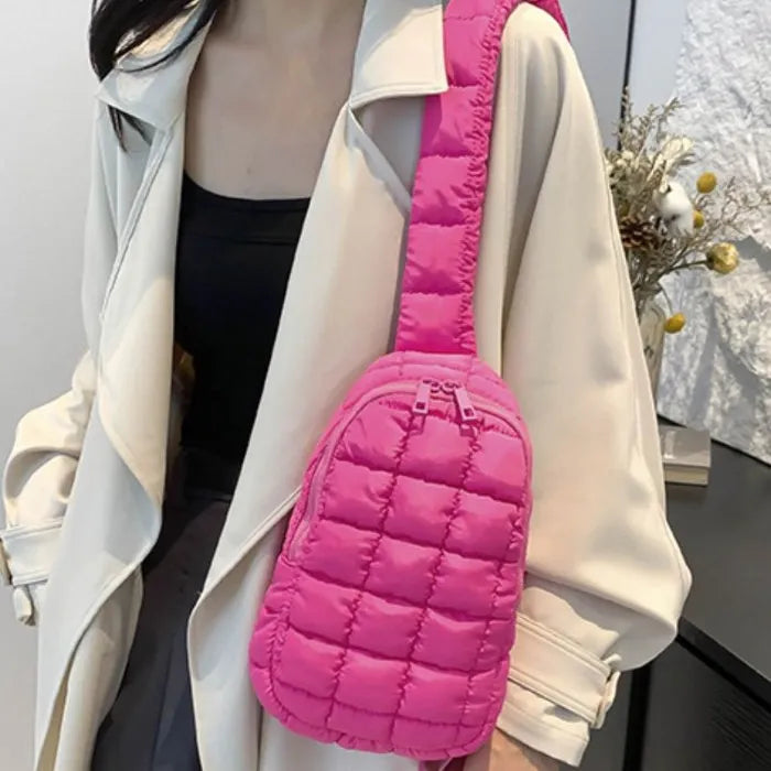 Person wearing cream coat with bright pink quilted crossbody bag, black top visible, dried flowers in background