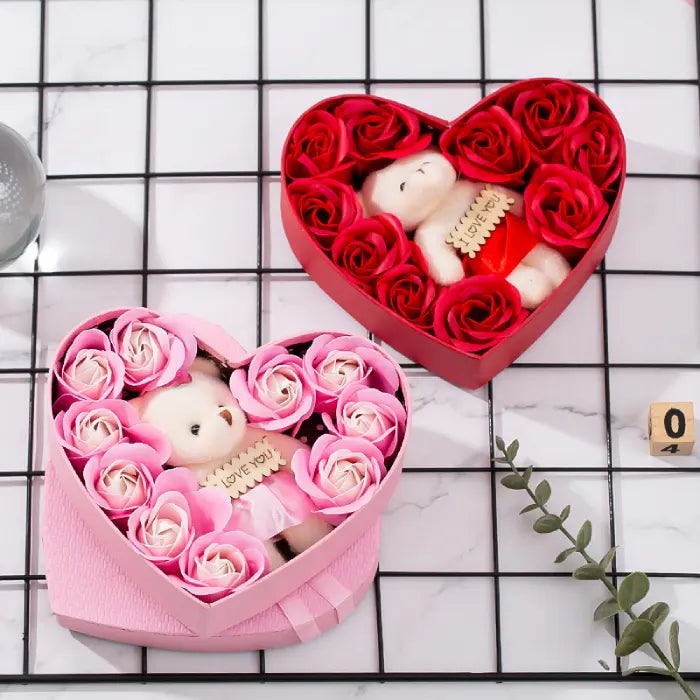 Open pink and red heart-shaped gift boxes with teddy bears and artificial roses for romantic gifting.