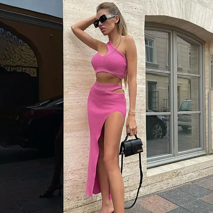 pink ribbed two-piece set with one-shoulder design and high-slit maxi skirt styled with sunglasses and black handbag