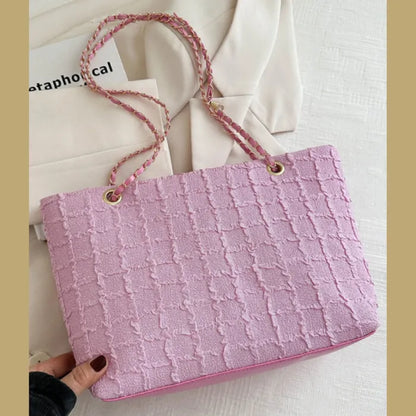 Pink textured handbag with matching chain strap on light background