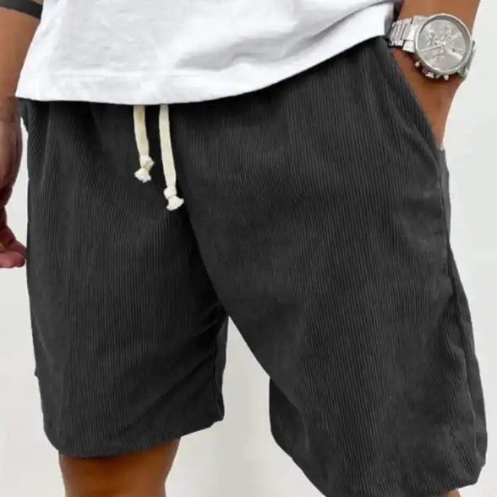 Size Men's Corduroy Shorts in black with drawstring waist and side pockets, worn with white shirt.