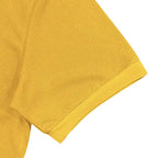 Close-up detail of plus size yellow polo shirt sleeve hem and textured waffle knit fabric.