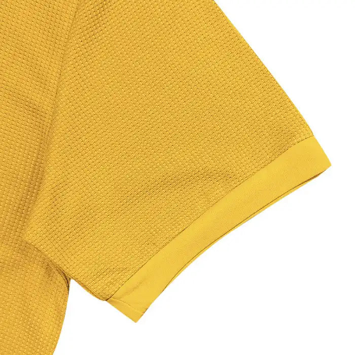 Close-up detail of plus size yellow polo shirt sleeve hem and textured waffle knit fabric.