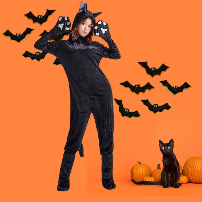 Plush black cat costume with bats, pumpkins, and kitten on orange Halloween-themed backdrop.