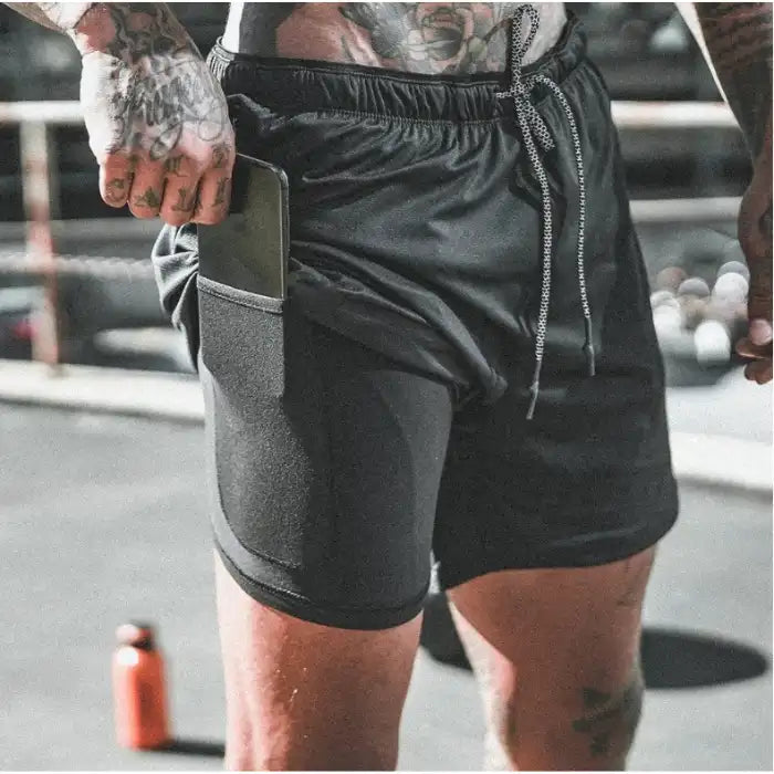 Black pocket compression shorts styled for gym use, showing phone in built-in thigh pocket.