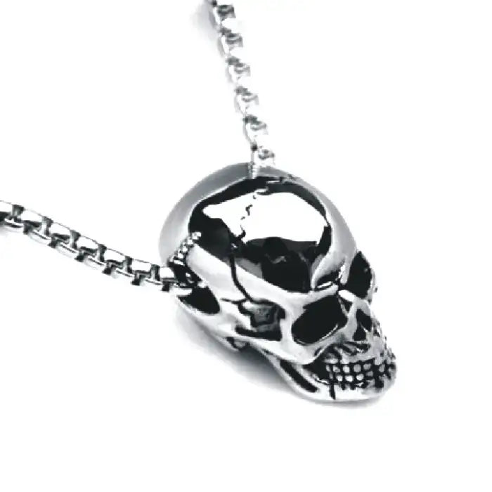 Close-up of a polished skull pendant on a sleek chain necklace with detailed craftsmanship.