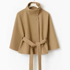 Poncho coat in camel color with short length and belted waist, displayed on hanger.