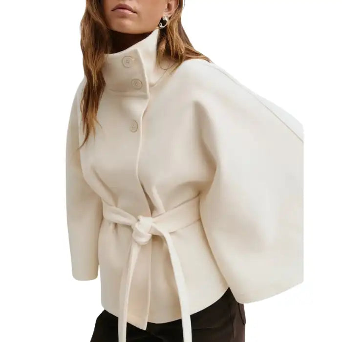 Cream wool poncho coat with tie belt and high neck, styled with dark trousers.
