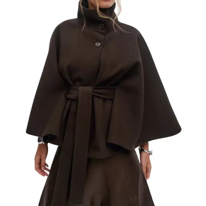 Poncho coat in dark brown with a sleek belted waist and flared silhouette, styled on model.